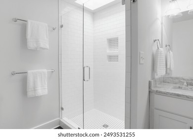 Minimalist White Bathroom With Large Glass-Enclosed Shower And Two Towels - Powered by Shutterstock