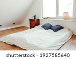 Minimalist white bed mattress on solid hardwood oak floor in cozy modern home bedroom. Minimalist white bright room.