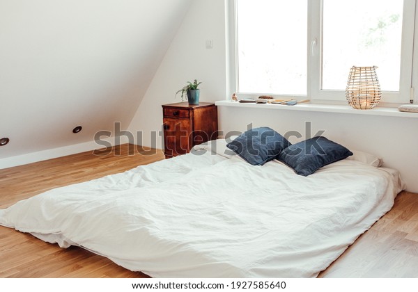 Minimalist white\
bed mattress on solid hardwood oak floor in cozy modern home\
bedroom. Minimalist white bright\
room.