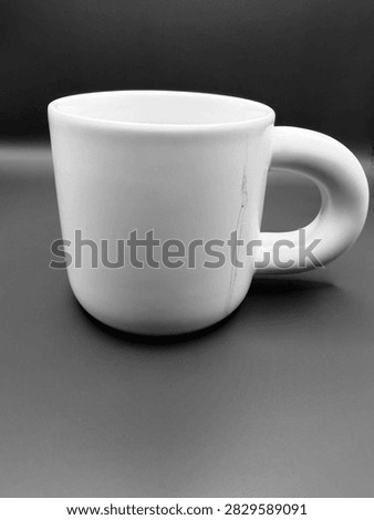 A minimalist white mug with a substantial rounded handle is isolated against a smooth dark gray backdrop.