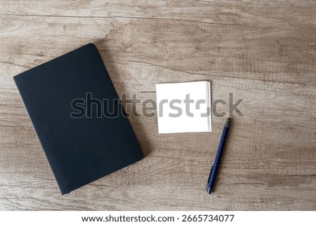 Minimalist workspace with notebook, blank notes and pen on rustic background
