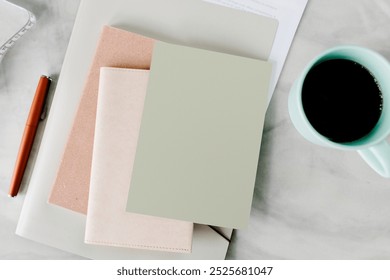 Minimalist workspace with notebooks, coffee, and pen. Neutral-toned notebooks, a green mug, and a pen, organized workspace vibe. Notebooks and coffee mug on the marble table. Small business workspace - Powered by Shutterstock