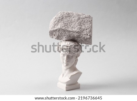 Minimalistic aesthetic composition of David's bust with a heavy stone balancing on his head. The concept of headache, migraine
