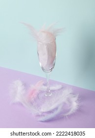 Minimalistic Aesthetic Still Life. Glass With Feathers On A Pastel Two Tone Background. Party Concept