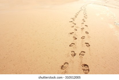 Minimalistic beach scene of two sets of foot prints in sand