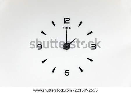 minimalistic black numbers and arrows of a wall clock on a white background