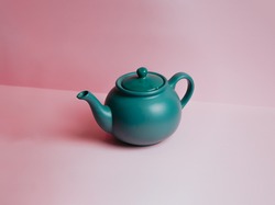 A Minimalistic Blue Teapot Over A Pastel Pink Background With Copy Space