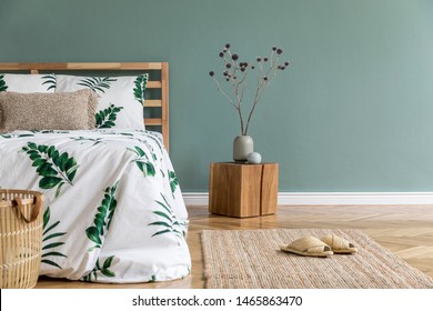 Minimalistic And Boho Interior Design Of Bedroom With Wooden Cube, Vase With Flowers, Rattan Basket, Carpet And Elegant Accessories. Beautiful Bed Sheets, Blankets And Pillows. Modern Home Decor.