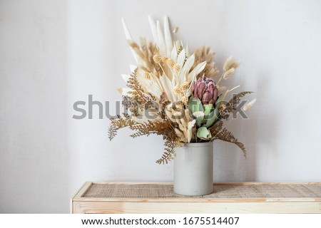 Minimalistic composition of dried flowers in cylindrical ceramic vase as home decoration. 