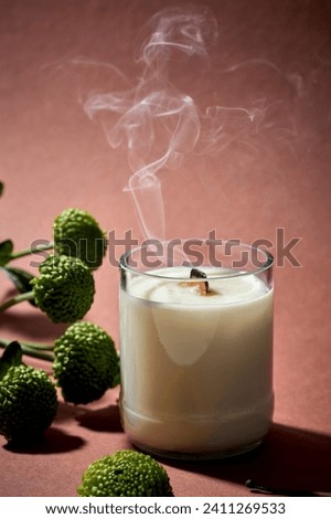 Minimalistic composition of an extinguished candle with smoke on a brown background with flowers. Aesthetics