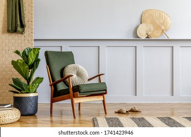 Minimalistic composition at living room interior with design armchair, beige panel, tropical plant, rattan pouf, book, shelf, copy space and elegant personal accessories in stylish home decor.