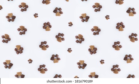 Minimalistic Creative Beautiful Pattern Of Dry Cat Food In The Shape Of Paws Of Different Sizes On A White Background.flat Lay.The Concept Of Proper Nutrition For Pets.Pet Store Poster Design