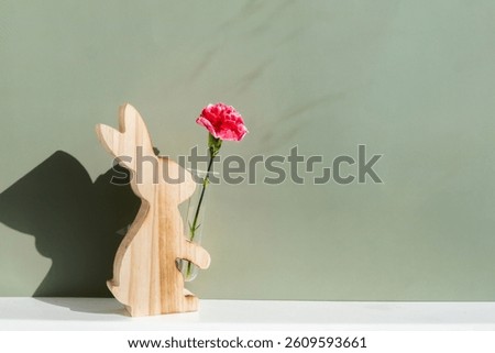 Minimalistic creative Easter concept. Two Easter bunnies under symbolic roof on green background. Celebration Easter holiday at home with family. Poster or greeting card