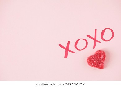 Minimalistic decor for Valentine's day with XOXO written sign and a red heart shaped candy with a copy space on light pink background - Powered by Shutterstock