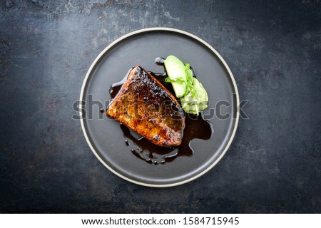 Minimalistic design Japanese salmon fish filet with avocado and wasabi creme glazed in teriyaki sauce as closeup on a modern design plate