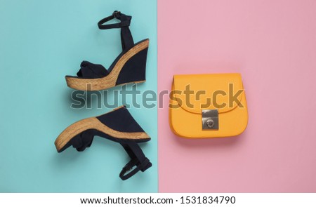 Minimalistic feshin still life. Sandals with platform, yellow leather bag on pink blue pastel background. Top view