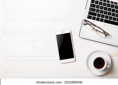 Minimalistic Flat Lay Composition Of Black & White Laptop Computer Keyboard, Cell Phone Gadget, Cup Of Coffee & Folded Glasses On Textured Wooden Desk Table Background. Workspace Top View, Copy Space