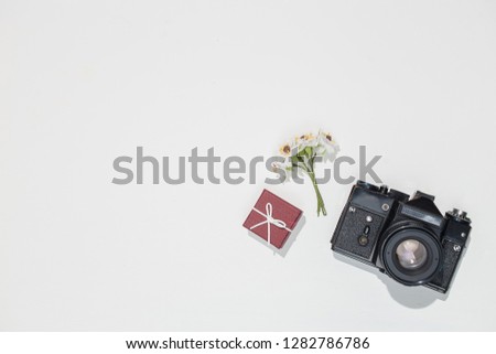 Minimalistic flat lay composition with retro camera, vinous gift box and spring field flower on white background. Trendy flat lay mockup for bloggers, designers, photographers, etc.