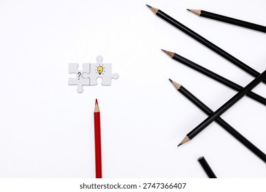 minimalistic flat lay image featuring black pencils scattered on white background and one red pencil standing out. Two connected puzzle pieces with question mark and light bulb icon symbolize idea generation, solution finding, creativity, innovation, leadership, and thinking differently. 