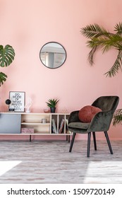 Minimalistic and luxury pastel pink home interior with green velvet design armchair, plants and mirror