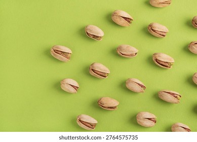 Minimalistic pattern featuring pistachio nuts arranged in a diagonal grid on a vivid green background. 