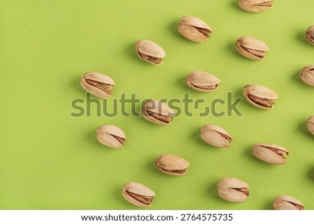 Minimalistic pattern featuring pistachio nuts arranged in a diagonal grid on a vivid green background. 