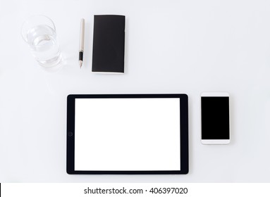 A minimalistic set of black and white business accessories and digital devices laying on a white table: a phone, a tablet, a notebook, a glass of water, top view mockup - Shutterstock ID 406397020