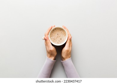 Minimalistic style woman hand holding a cup of coffee on Colored background. Flat lay, top view cappuccino cup. Empty place for text, copy space. Coffee addiction. Top view, flat lay. - Powered by Shutterstock