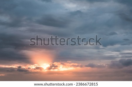Minimalistic sunset cloudy sky with orange sun breaking through the clouds