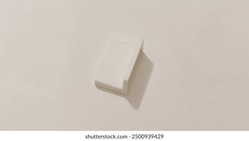 Minimalistic white rectangular object with perpendicular edge, casting soft shadow on light background.