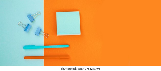 Minimum Set Of School And Office Supplies On Bright Blue (turquoise) And Orange Background: Pen, Clips, Note Paper. Concept: Back To School. Flatlay, Top View.