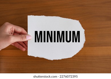 Minimum. Woman hand holds a piece of paper with the note,  minimum. Weight,  smallest, volume, number, quantity, amount, minimal and lowest.