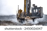 Mining drilling machine working at open pit in a cloud of dust for blasting activities