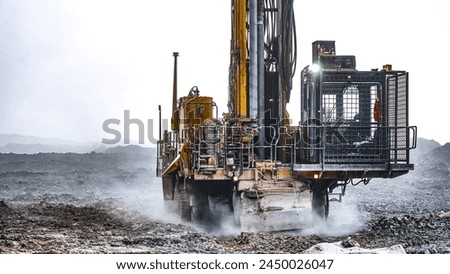 Mining drilling machine working at open pit in a cloud of dust for blasting activities