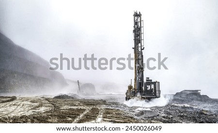 Mining drilling machine working at open pit in a cloud of dust for blasting activities
