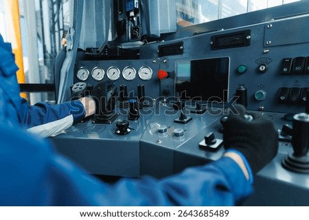 Mining equipment control panel with operator using levers and buttons in industrial setting.