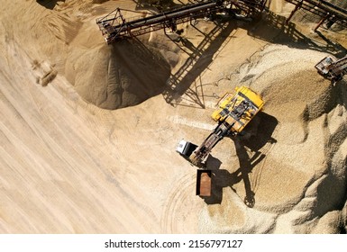 Mining excavator with electric shovel loading sand into haul truck in opencast. Belt conveyor and Sand Making Plant in open-pit. Sand crushing and bulk materials for construction industry.
