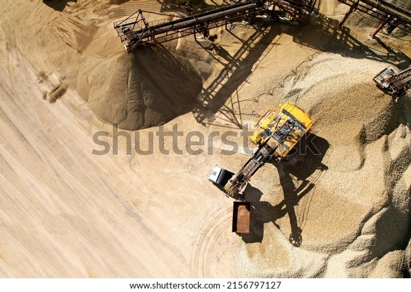 Mining excavator with electric shovel loading\
sand into haul truck in opencast. Belt conveyor and Sand Making\
Plant in open-pit. Sand crushing and bulk materials for\
construction industry.\

