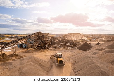 Mining excavator loading sand on belt conveyor in opencast, aerial top view. Open pit mine concept.