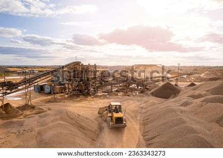 Mining excavator loading sand on belt conveyor in opencast, aerial top view. Open pit mine concept.