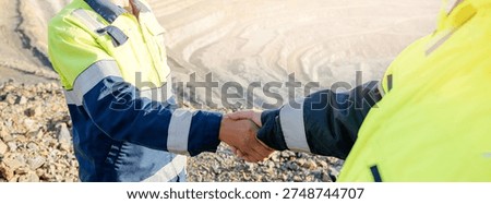 Mining Industry Agreement, Two Engineers Shaking Hands at Open-Pit Mine of ore.