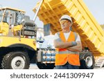 Mining industry truck driver in hard hat on background cabin of his lorry. Concept industrial logistic.