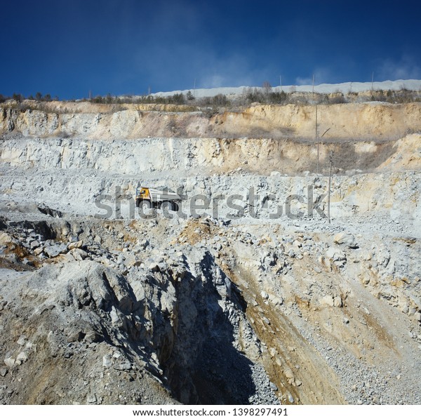 Mining truck transports\
the extracted ore against the background of the stone quarry\
relief, panorama.