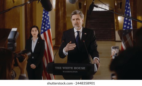 Minister or congressman speaks at press conference in the White House, gives interview for media. US presidential candidate pronounces inspirational campaign speech. American flags in the background. - Powered by Shutterstock