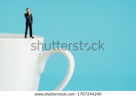 miniture business model standing on hot coffice cup.