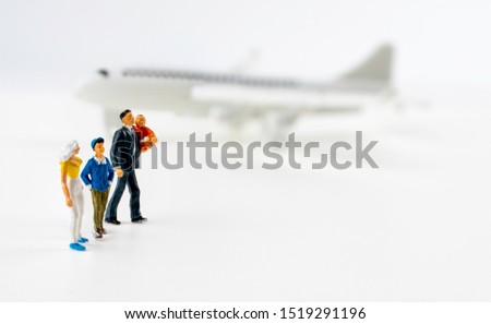 miniture family of father mother son and daughter travelling and doing business with blurred airplane behind on isolated white background