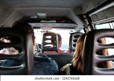 Minivan Passengers Share A Ride: Group Of People Traveling In A Minivan Shot From Backseat