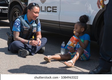 MINNEAPOLIS - May 6, 2018: An unidentified child waits with police officers as they attempt to locate her guardian after Minneapolis's yearly May Day parade. 