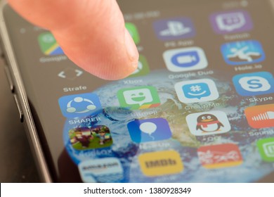 MINNEAPOLIS, MINNESOTA / USA - APRIL 25, 2019: Person using Apple i-phone to press and access the Bitmoji app / application