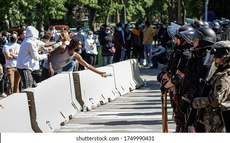 Minneapolis, MN/USA - May 30th 2020: Young Black Man Reaches Over Barrier To Offer Water To Police Officers In Riot Gear In South Minneapolis. 